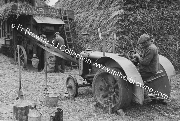 THRESHING SCENE MAN CONTROLLING TRACTOR WHICH IS POWERING THRESHER